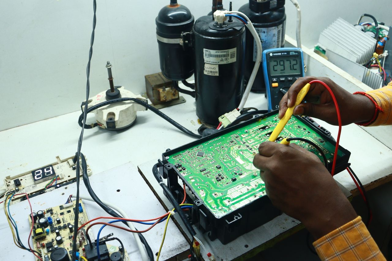 Crafting Captivating Headlines: Your awesome post title goes here Technician working on AC PCB with tools and equipment, captured in New Delhi workshop.